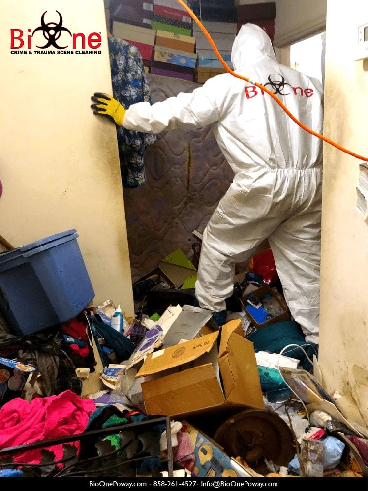 Image shows Bio-One technician making its way through a pile of clutter and debris.